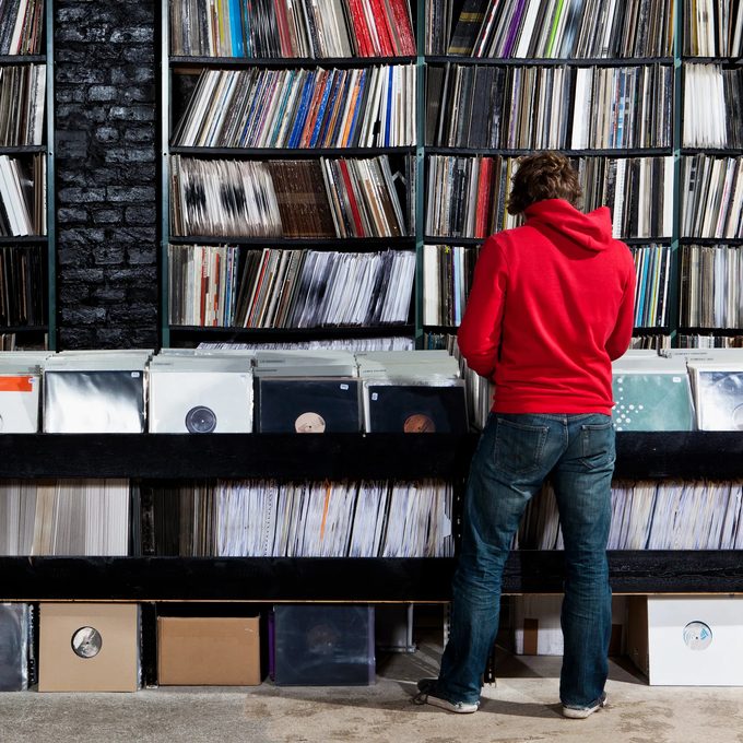 A shopper flipping through crates of vinyl records against a wall of record shelves
