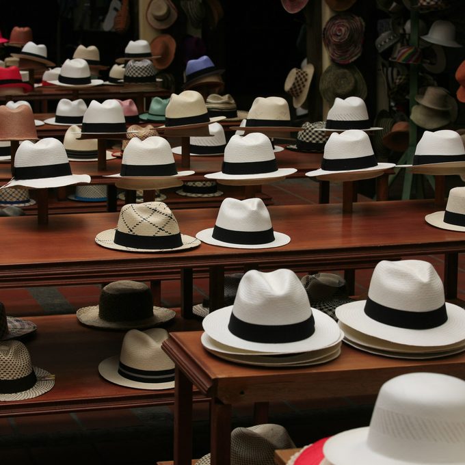 Rows of straw panama and fedora hats displayed on wooden tables in a hat shop